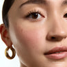 Close-up of a person's face with a gold hoop earring and visible mascara.