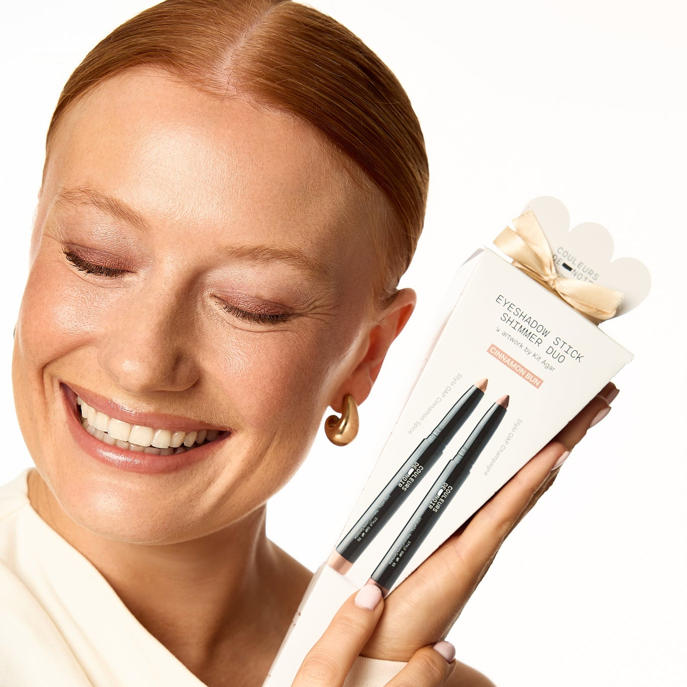 Woman holding a box of makeup brushes with a neutral background