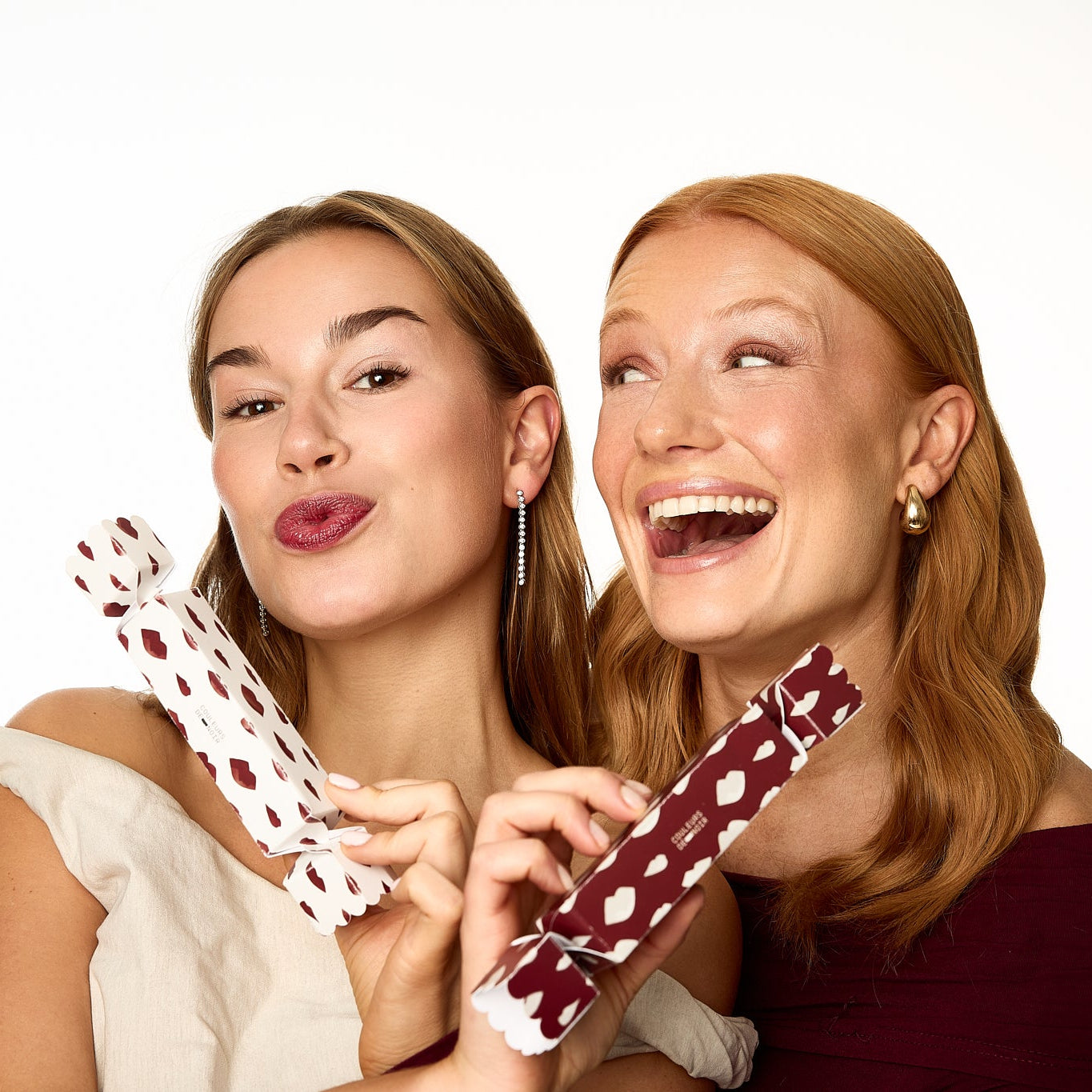 Two women holding polka dot items against a white background
