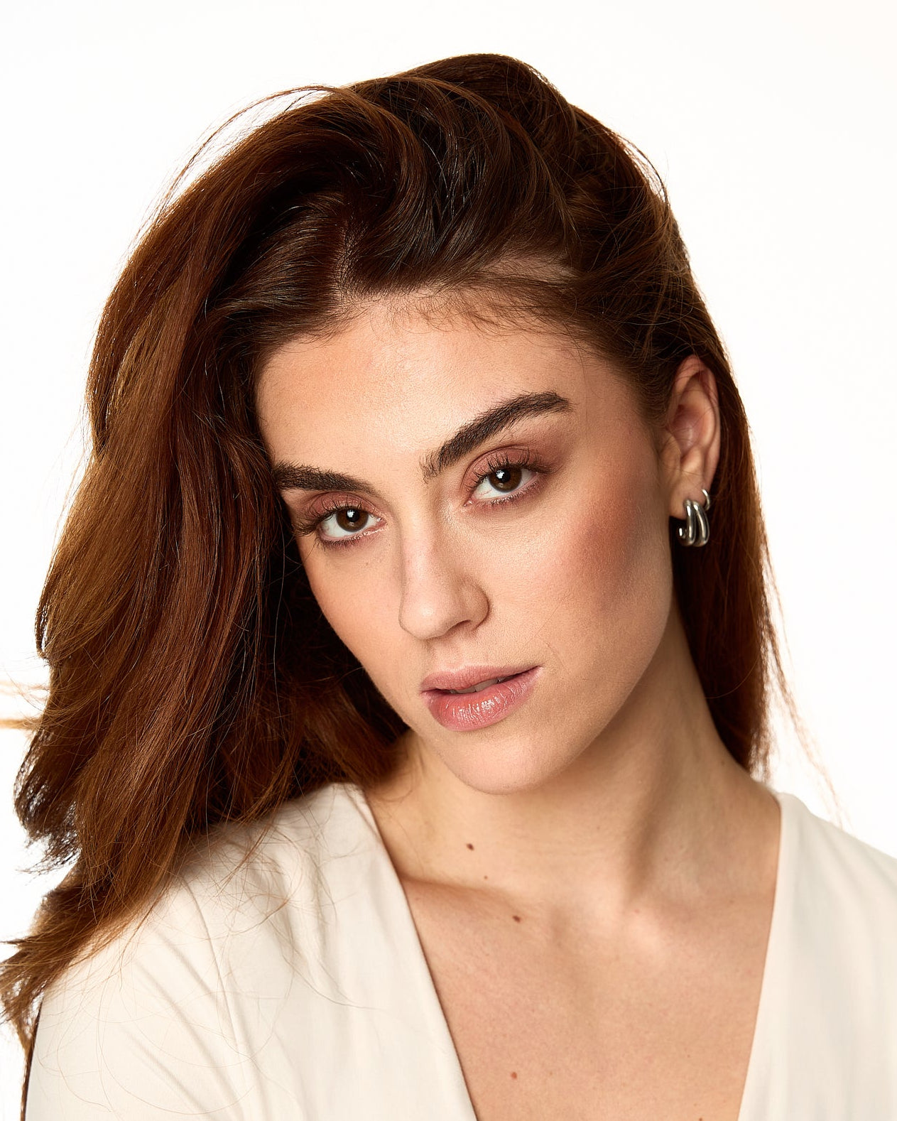 Woman with long brown hair wearing a white top on a white background