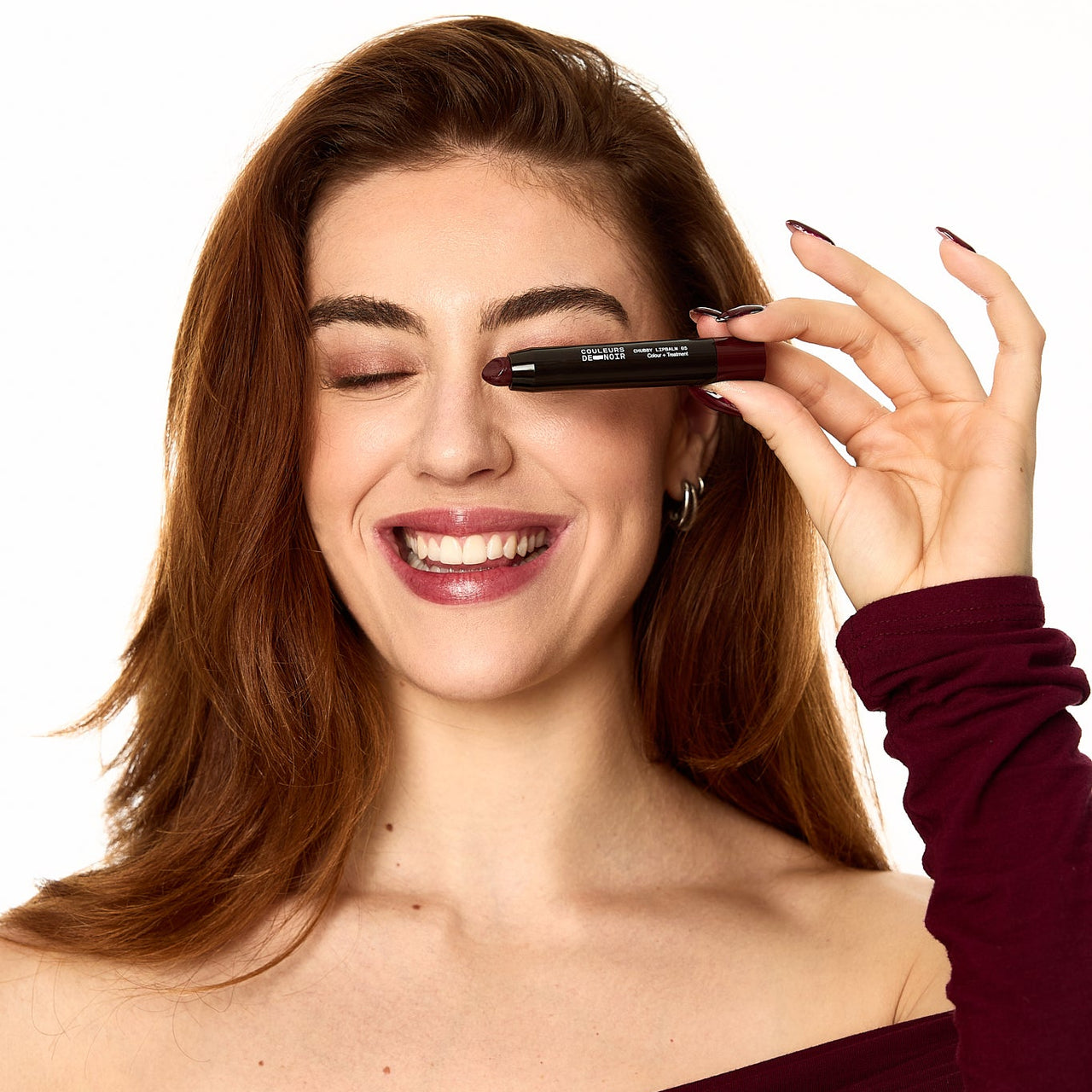 Woman applying eyeliner with a brush on a white background
