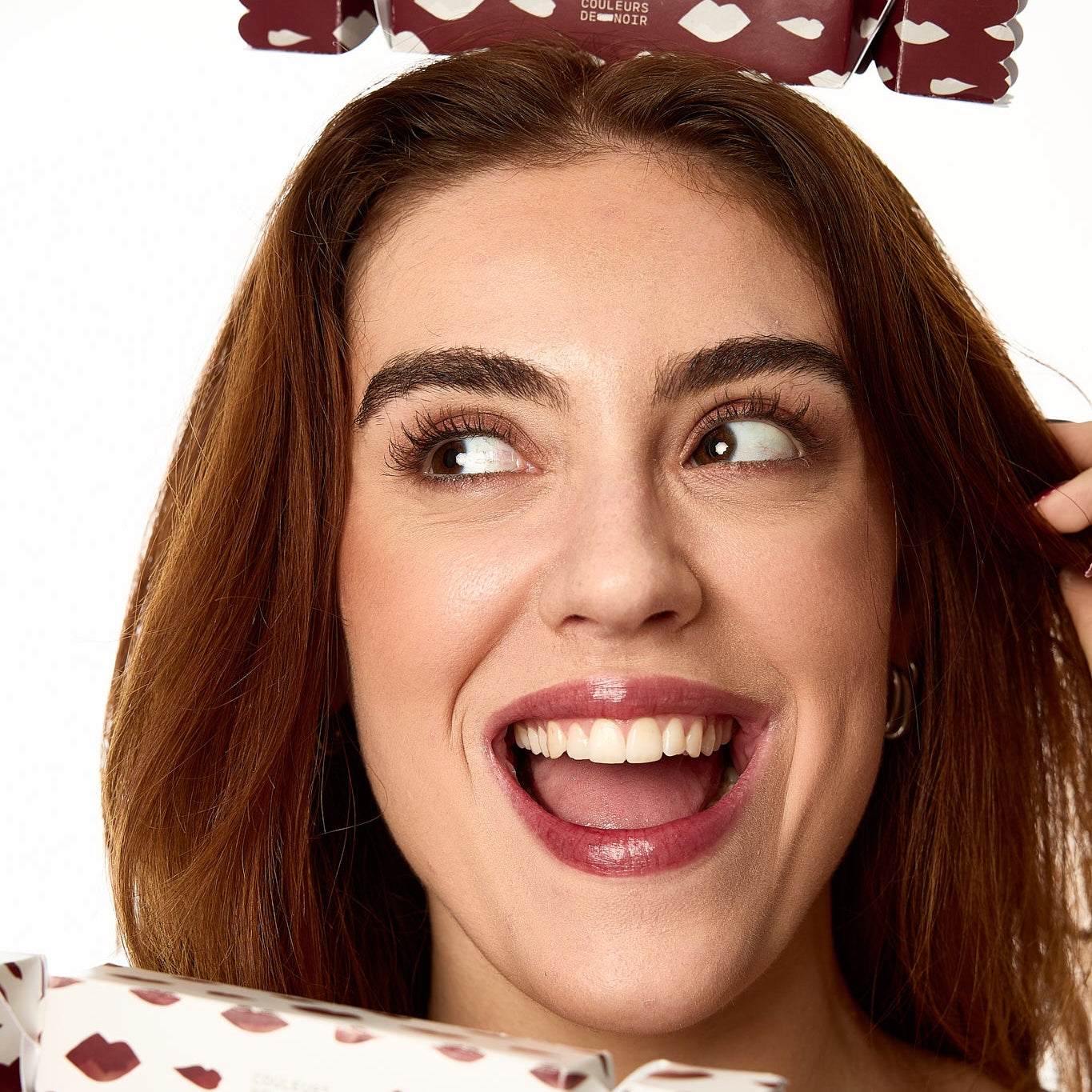 Woman with a cracker on her head and another cracker in front of her face on a white background