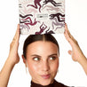 Woman holding a decorative box with abstract designs above her head on a white background