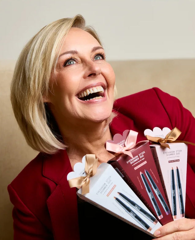 Woman in a red coat holding gift boxes with bows on a beige couch.