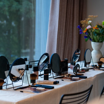 Table with makeup mirrors and products near a window with curtains