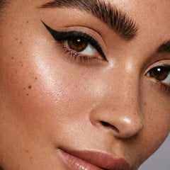 Close-up of a woman's face with defined eye makeup on a neutral background